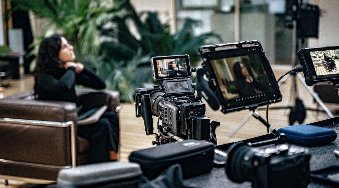 Tournage d’une interview en intérieur avec plusieurs caméras et moniteurs, face à une femme assise.