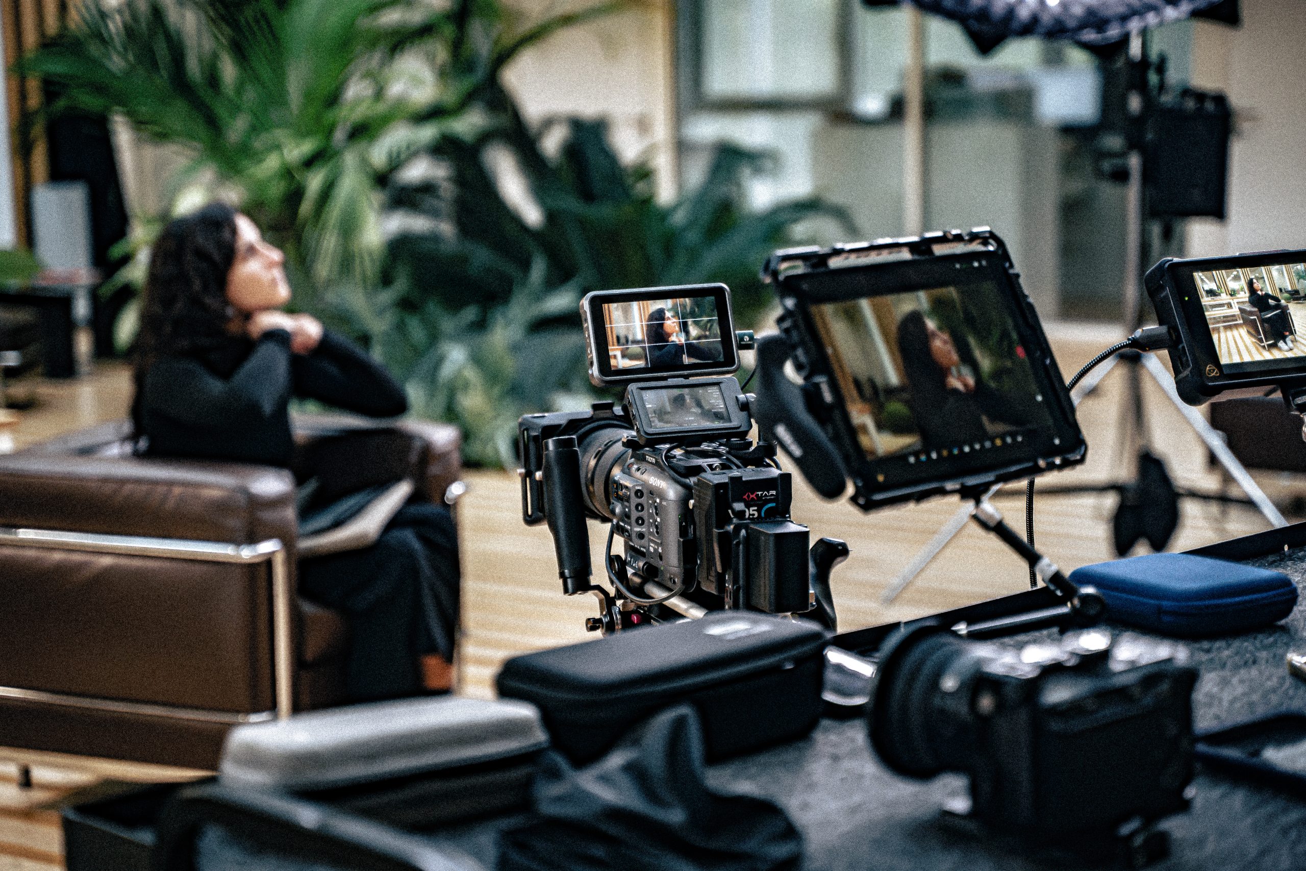 Tournage d’une interview en intérieur avec plusieurs caméras et moniteurs, face à une femme assise.