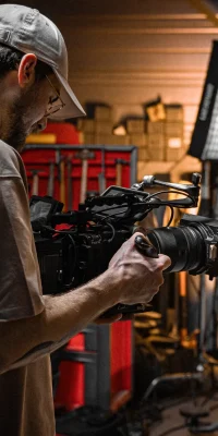 Un vidéaste ajuste une caméra professionnelle dans un studio éclairé par un projecteur LED.