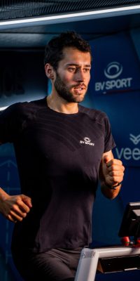 Athlète courant sur un tapis de course pendant un test d’effort, filmé par un cadreur en laboratoire de performance.