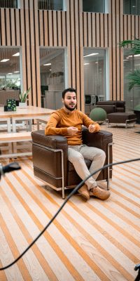 Tournage d’une interview en intérieur avec deux caméras sur trépied et un homme assis dans un fauteuil.