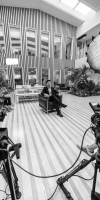 Tournage d’une interview, avec deux caméras et un éclairage, dans un grand hall intérieur d'une entreprise.