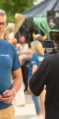 Interview en extérieur : un cadreur Blaak Production filme un homme en t-shirt bleu lors d’un événement.